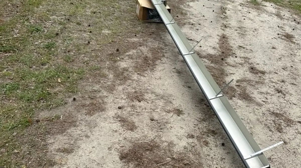 On-site seamless gutter fabrication showing long aluminum gutter being custom made in Branchville SC